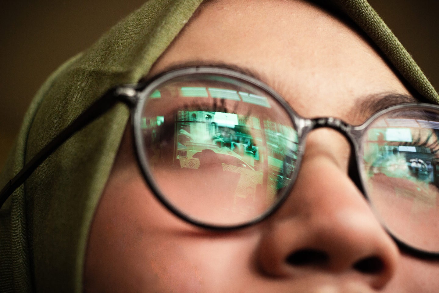 A women with glasses and the reflection of a computer screen in her lenses.