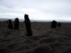 An underexposed photo sandy beach with wood pylons.